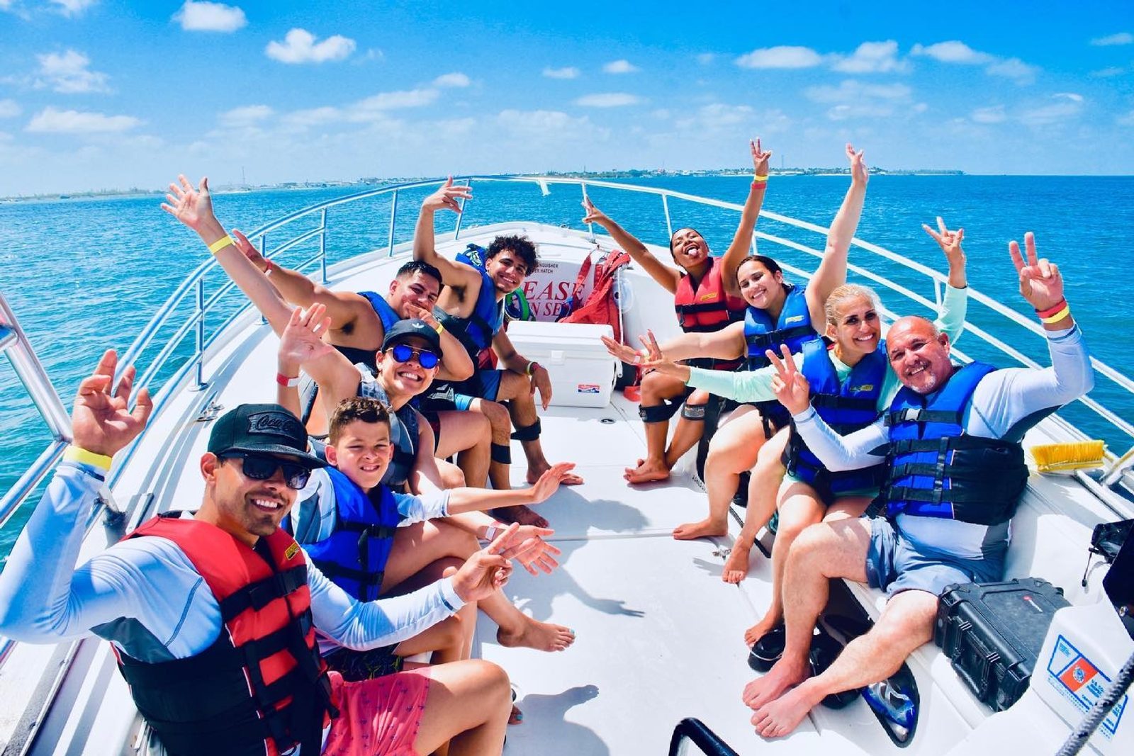 A full boat of guests in life jackets cheering and throwing peace signs on the parasail boat with Key West water behind them