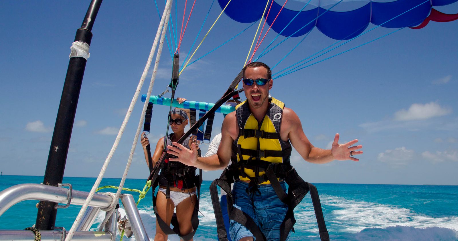 A father in a yellow life jacket and his young daughter clipped into the parasail harness on the flight deck, moments before takeoff